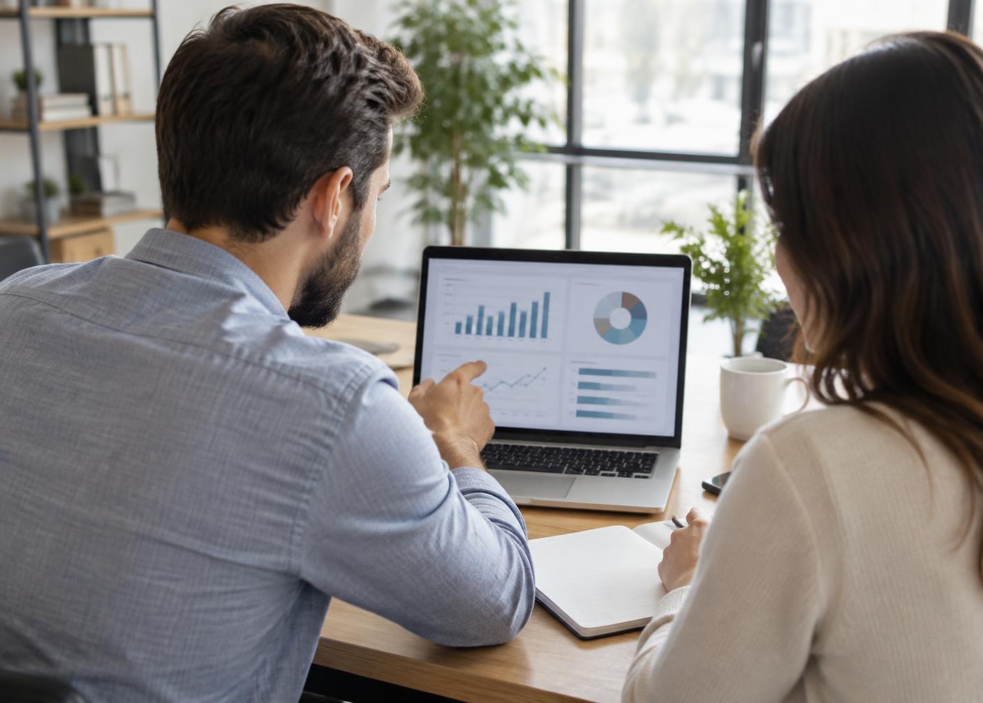 Two colleagues reviewing charts on a laptop